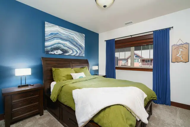 Fresh green bedding and soft lighting give the second bedroom a welcoming feel at Riverstone Village Retreat, Coeur d'Alene Idaho