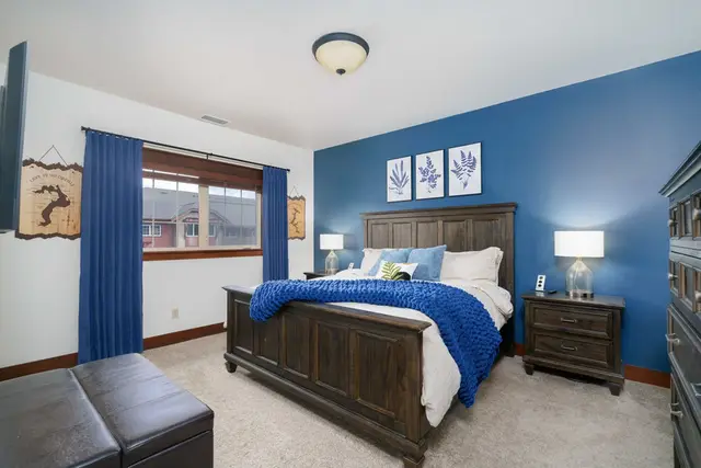 Rest easy in a bright bedroom with blue accents, warm wood furniture, and bedside lamps at Riverstone Village Retreat, Coeur d'Alene Idaho