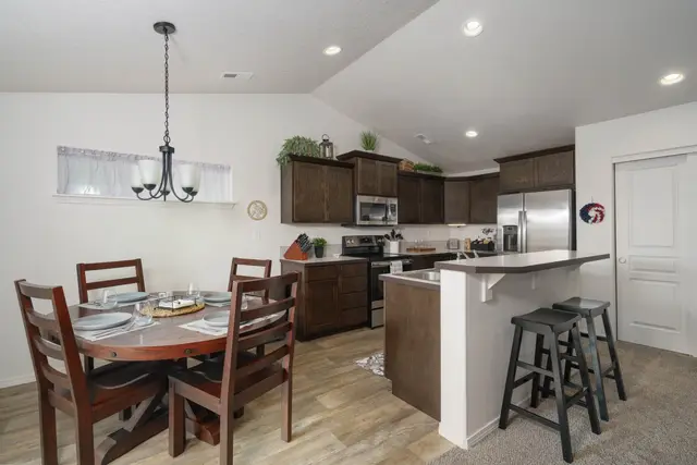 A fully equipped kitchen opens to a family dining table set for gathering—cook together at Pine and Vine Cottage, Rathdrum Idaho