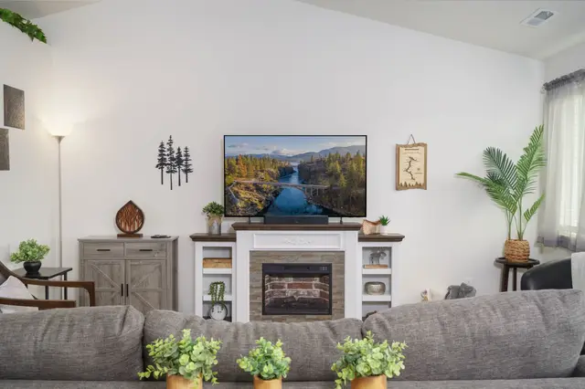 Movie nights come alive here—a big smart TV above a warm fireplace and a deep sectional at Pine and Vine Cottage, Rathdrum Idaho