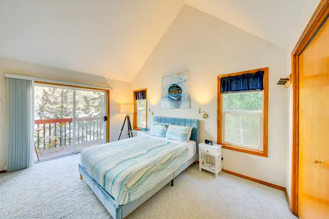 Queen bed in upstairs loft with direct view of the the lake through the trees at Bay-View Cabin, Bayview Idaho